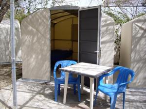einen Tisch und zwei blaue Stühle neben einem Zelt in der Unterkunft Camping Koula in Parikia