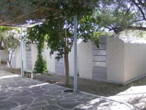 a white wall with a bench next to a tree at Camping Koula in Parikia