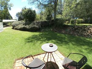 a patio with two chairs and a table in a yard at Sani's Rest in Himeville