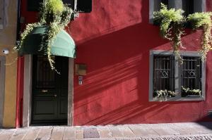 un bâtiment rouge avec une porte noire et deux fenêtres dans l'établissement Al Palazzetto, à Udine