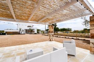 an outdoor patio with white chairs and a pergola at Sea Salento Casa Vacanze in Punta Prosciutto