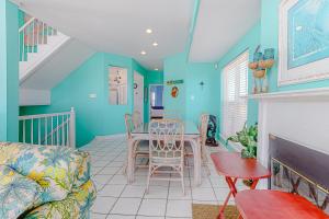 een woonkamer met blauwe muren en een tafel en stoelen bij Dolphin View by Meyer Vacation Rentals in Gulf Shores