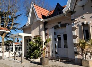 Casa blanca con techo rojo en Hôtel Villa Teranga, en Andernos-les-Bains