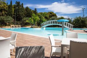 a swimming pool with a white bridge and chairs at Villaggio Marinella DIRETTAMENTE sul mare in Isola Capo Rizzuto