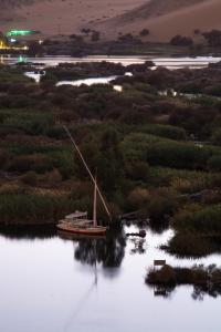 a boat sitting on the water at night at ASWAN NILE PALACE (swimming pool-rooftop-Nile view) in Aswan