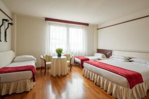 a room with two beds and a table with chairs at Hotel Leopardi in Verona