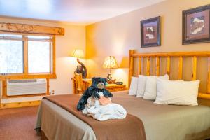a teddy bear sitting on a bed in a bedroom at Spearfish Canyon Lodge in Spearfish