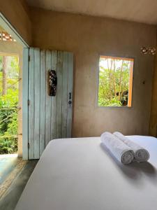 1 dormitorio con 1 cama con 2 toallas en Eco Casa di Barro Hospedagem e Hostel, en Isla de Boipeba