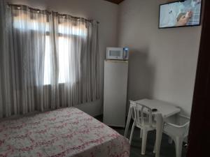 um quarto com uma cama, uma mesa e uma televisão em Pousada Familiar Morada do Rapha em Boraceia