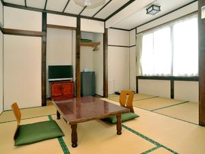 Ryokan Seifuso - Vacation STAY 85475v في ماتسوموتو: غرفة معيشة مع طاولة وكراسي خشبية