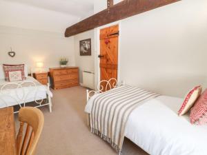 1 dormitorio con 2 camas y puerta de madera en Beechcroft Cottage en South Molton