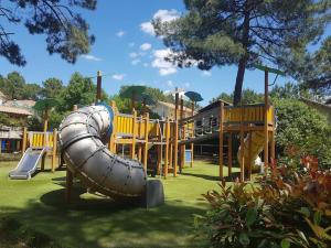 a playground with a slide in a park at Maison sur golf avec piscine chauffée à Lacanau Océan in Lacanau