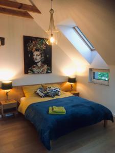 a bedroom with a blue bed with a painting on the wall at La Jaguara artistic house in the center of Gdansk in Gdańsk