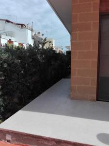 a sidewalk next to a brick building with bushes at B & B La Magnolia in Specchiolla