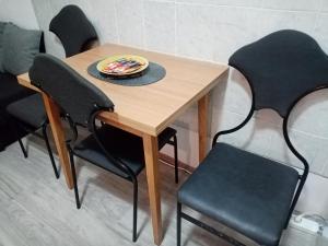 einem Holztisch mit schwarzen Stühlen und einem Teller darauf in der Unterkunft Apartment Anna in Belgrad