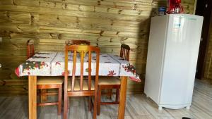a table and chairs with a table and a refrigerator at Cabana Bacana in Praia Grande