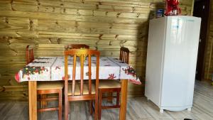 a table and chairs with a table and a refrigerator at Cabana Bacana in Praia Grande