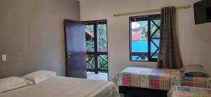 een slaapkamer met 2 bedden en een glazen schuifdeur bij Pousada das Pedras in Toque Toque Pequeno