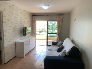 een woonkamer met een bank en een televisie bij Apartamento no Aquaville Resort, do lado da sombra e perto da praia in Aquiraz