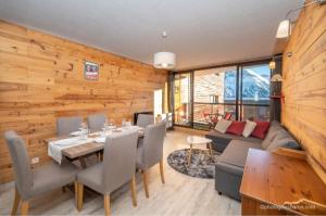 ein Esszimmer und ein Wohnzimmer mit einer Holzwand in der Unterkunft Appartement Queyrelet Orcières in Orcières