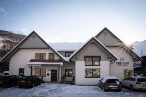 Biały dom z samochodami zaparkowanymi na śniegu w obiekcie Appartements Freiraum w Schladming
