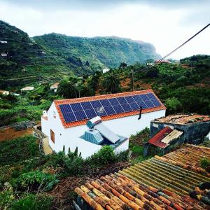 Sustainable Rural House La Lisa Dorada في Agulo: منزل أبيض مع لوحات شمسية على سقفه