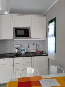a kitchen with white cabinets and a table with chairs at La Casa De MarcoQ in Costa Calma