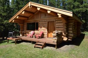 a log cabin with a deck with chairs and a table at Rocky Mountain Escape Log Cabin Rentals - Rock Lake in Rock Lake Lodge Provincial Park