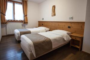 1 dormitorio con 2 camas y ventana en lareit appartamenti, en Bormio