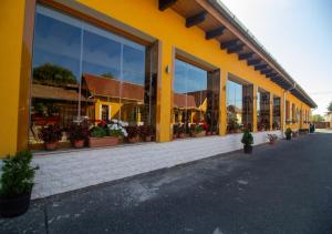 a yellow building with lots of windows and potted plants at Radics Panzió Étterem és Pihenő Központ in Letenye