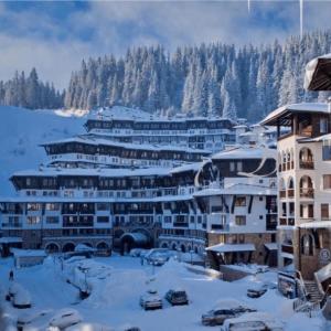 een resort in de sneeuw met auto's voor de deur bij Гранд Манастира Частен Апартамент in Pamporovo