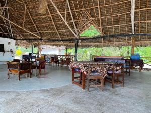 a group of tables and chairs under a straw roof at Menai Bay Beach Bungalows in Unguja Ukuu