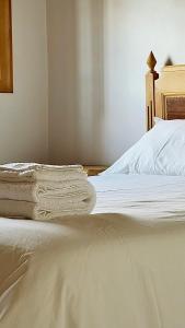 uma cama com lenis brancos e uma cabeceira de madeira em Casa do Rio Alva em Arganil mais 15 fotografias