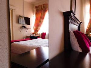 a reflection of a bedroom with a bed and a mirror at The Haven Guest House in Mbabane