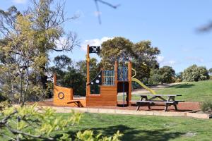 un parque infantil con mesa de picnic y banco en Riverfront Motel & Villas, en Hobart