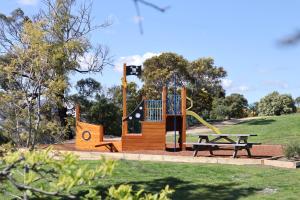 um parque infantil num parque com uma mesa de piquenique e um banco em Riverfront Motel & Villas em Hobart
