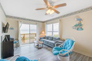 a living room with a couch and a ceiling fan at 1 Anchors Away Oceanfront in Holden Beach