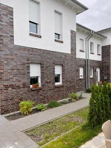 ein Backsteingebäude mit zwei Fenstern und einem Gehweg in der Unterkunft Lux Apartmant 2 Westerstede in Westerstede