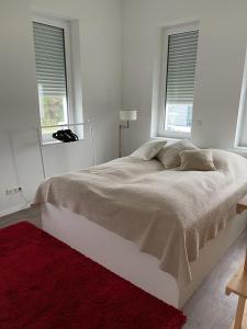 ein weißes Schlafzimmer mit einem großen Bett und zwei Fenstern in der Unterkunft Lux Apartmant 2 Westerstede in Westerstede