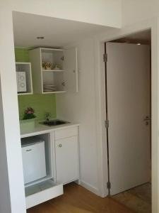 a kitchen with white cabinets and a sink and a door at Studios Greenside in Coimbra