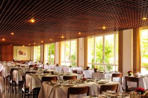 a banquet hall with white tables and chairs and windows at Hotel Majestic in Águas de Lindóia