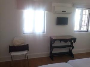a bedroom with a desk and a chair and windows at Studios Greenside in Coimbra