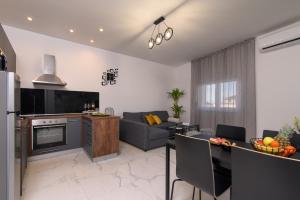 cocina y sala de estar con sofá y TV en Batinic Apartments, en Kaštela