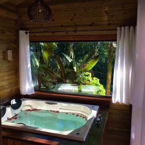 a bath tub in a room with a window at Pousada Village dos Canyons in Praia Grande