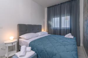 Un dormitorio con una gran cama azul y una ventana en Batinic Apartments, en Kaštela