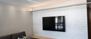 a flat screen tv mounted on a white brick wall at Itacimirim Apartments Ondas in Itacimirim