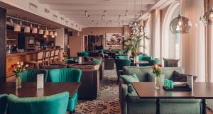 a restaurant with green chairs and tables and a bar at Radisson Blu Aleksanteri Hotel, Helsinki in Helsinki