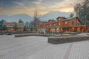 a large building with mountains in the background at Radisson Golf Resort Pahalgam in Pahalgām
