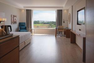 a hotel room with a bed and a large window at The Elite Narasapura, a member of Radisson Individuals in Narasapura