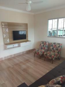 ein Wohnzimmer mit einem Sofa und einem Flachbild-TV in der Unterkunft Casa em Guarapari, próximo a praia do morro in Guarapari